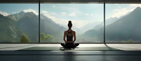 A woman in a yoga studio doing cobra pose on a mat by a large window photo