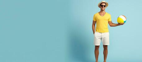 Happy man in summer attire holding beach ball and looking at empty space enjoying vacation on blue backdrop photo