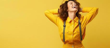 Middle aged woman joyfully poses in orange overalls with bright makeup against a yellow background displaying lively movements and leaving room for text photo