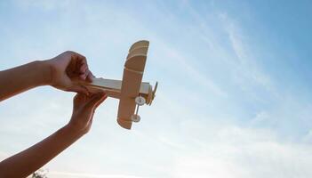 contento niños jugando un de madera juguete avión en el puesta de sol cielo antecedentes. foto