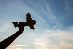 Silhouette of happy children playing a wooden toy plane on the sunset sky background. photo