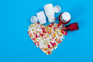 Medical pills and tablets spilling out of a drug bottle on blue background photo