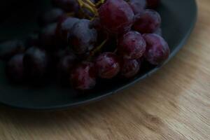 Close-up of grapes with water droplets on a black ceramic plate. photo