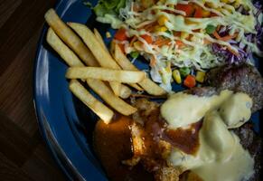 queso Cerdo filete en un negro plato con vegetal ensalada foto