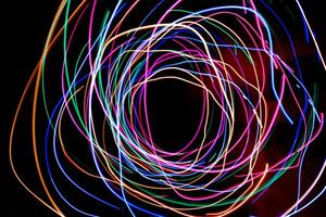 Multi color light painting photography, swirl and curve of blue, green and red light against a black background. photo