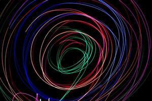 Multi color light painting photography, swirl and curve of blue, green and red light against a black background. photo