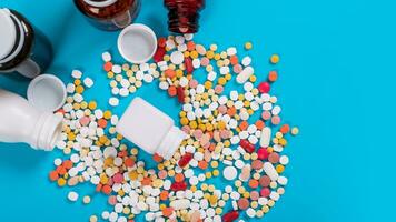 Medical pills and tablets spilling out of a drug bottle on blue background photo