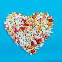 Many pills in the form of a heart Multicolored on a blue background photo