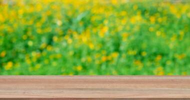 Wooden table with flowers field blurred background. photo
