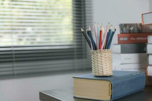 School supplies on wooden table in warm interior, school books on table, education concept. photo