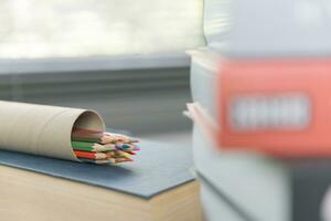 School supplies on wooden table in warm interior, school books on table, education concept. photo