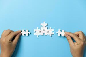 Two hands trying to connect couple puzzle piece on blue background. Teamwork concept. Closeup hand of connecting jigsaw puzzle. photo