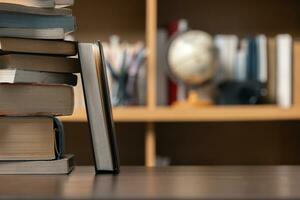 Education learning concept. Book in library with old open textbook, stack piles of literature text archive on reading desk, aisle of bookshelves in school study class room background for academic photo