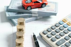 Top view of miniature car model, calculator and pen on office desk table. Business, finance, saving money, banking or car loan concept. Car, coins and calculator with copy space. photo