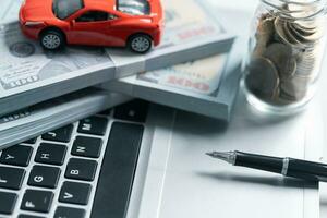 Top view of miniature car model, calculator and pen on office desk table. Business, finance, saving money, banking or car loan concept. Car, coins and calculator with copy space. photo