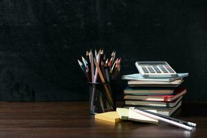 Back to school background with books on wooden table over chalkboard photo