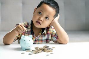 preescolar niño aprendizaje a calcular personal presupuesto, gestionar finanzas, jugando inversión, contabilidad. enfocado colegio niño ahorro dinero para compra, poniendo efectivo en rosado cerdito banco a hogar. foto