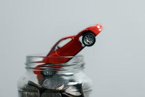 Miniature car model and Financial statement with coins. Finance and car loan, saving money for a car concepts. Car loan, money, banknote on agreement document or car insurance application form. photo