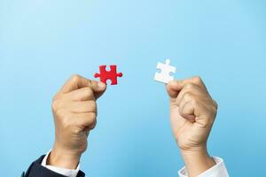 Two hands trying to connect couple puzzle piece on blue background. Teamwork concept. Closeup hand of connecting jigsaw puzzle. photo