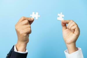 Two hands trying to connect couple puzzle piece on blue background. Teamwork concept. Closeup hand of connecting jigsaw puzzle. photo