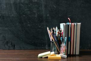 Back to school background with books on wooden table over chalkboard photo