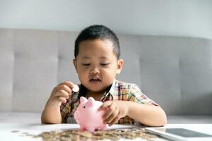 Preschooler child learning to calculate personal budget, manage finance, playing investment, accounting. Focused school kid saving money for purchase, putting cash in pink piggy bank at home. photo