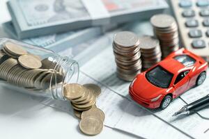 Top view of miniature car model, calculator and pen on office desk table. Business, finance, saving money, banking or car loan concept. Car, coins and calculator with copy space. photo