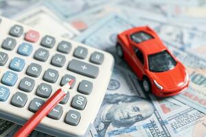 Top view of miniature car model, calculator and pen on office desk table. Business, finance, saving money, banking or car loan concept. Car, coins and calculator with copy space. photo