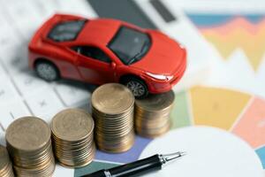 Miniature car model and Financial statement with coins. Finance and car loan, saving money for a car concepts. Car loan, money, banknote on agreement document or car insurance application form. photo