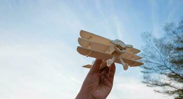 Freedom concept, human hand holding wooden plane on the sunset sky background photo