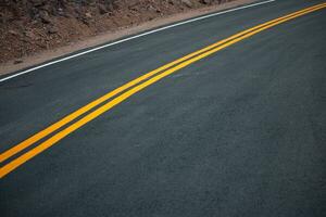 el asfalto la carretera tiene amarillo y blanco tráfico líneas cruce el montañas. foto