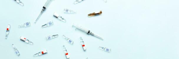 Banner Pattern of ampoules and syringes. Vaccination. Bird flu. Covid 19. Flat lay ampoules and medicines on a blue background photo