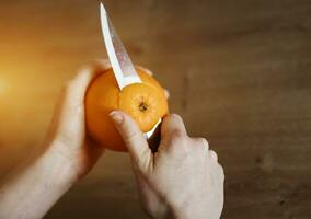 hands peeling orange knife photo