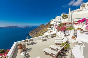 Amazing tranquil landscape of Santorini caldera and sea view, relaxing flowers, chaise lounge with white architecture. Fantastic summer scenic as vacation, travel holiday concept banner. Luxury vibes photo