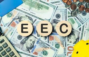 EEC text in wooden circle on Banknotes background, credit card, piggybank, calculator. european economic commission, planning goals, opportunity, challenge, business strategy and financial concept. photo