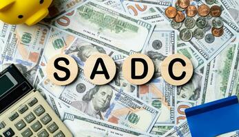 SADC text in wooden circle on Banknotes background, credit card, piggybank, calculator. Southern African Development Community, planning goals, opportunity, business strategy and financial concept. photo