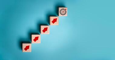 Virtual target board and increasing arrow icon on wooden cube. Business achievement goal and objective target concept. Blue background with copy space. photo