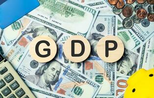 GDP text in wooden circle on Banknotes background, credit card, piggybank, calculator. Gross Domestic Product, economic, planning goals, opportunity, business strategy and financial concept. photo