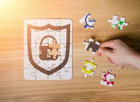 The cybersecurity symbol on missing puzzle piece with wood background. Man hand placing the last jigsaw with lock icon as security concept photo