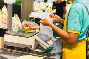 Grocery Store staff weighing fresh salas in plastic box on digital scales. photo