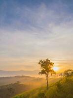 The breathtaking view in Nakhornsrithammarat, Thailand, as seen from the point of view of a tourist, with the hill being surrounded by fog and a golden sky in the background. photo