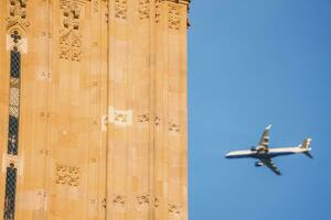 Airplane flying by Big Ben with clear blue sky in background photo