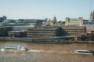 Cruise moving on river Thames by downtown district on sunny day photo