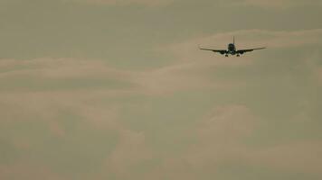 Airplane approaching to land at sunset. Airliner flight, illuminated sky background. Cinematic shot of an airplane in slow motion decline. Tourism and travel concept video