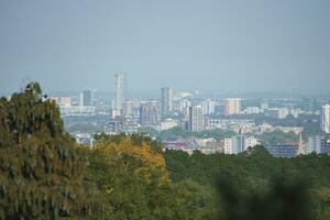 Scenic view of cityscape and trees with blue sky in background at London photo