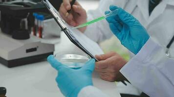 Health care researchers working in life science laboratory. Young female research scientist and senior male supervisor preparing and analyzing microscope slides in research lab. video