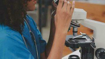 chercheurs en soins de santé travaillant dans un laboratoire de sciences de la vie. jeune chercheuse et superviseur masculin principal préparant et analysant des lames de microscope dans un laboratoire de recherche. video