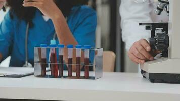 Health care researchers working in life science laboratory. Young female research scientist and senior male supervisor preparing and analyzing microscope slides in research lab. video