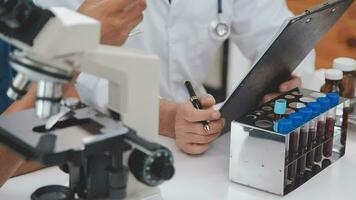 investigadores de atención médica que trabajan en el laboratorio de ciencias de la vida. joven científica investigadora y supervisora masculina senior preparando y analizando portaobjetos de microscopio en el laboratorio de investigación. video