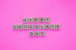 September 13, International Chocolate Day, minimalistic banner with the inscription in wooden letters on a pink background photo